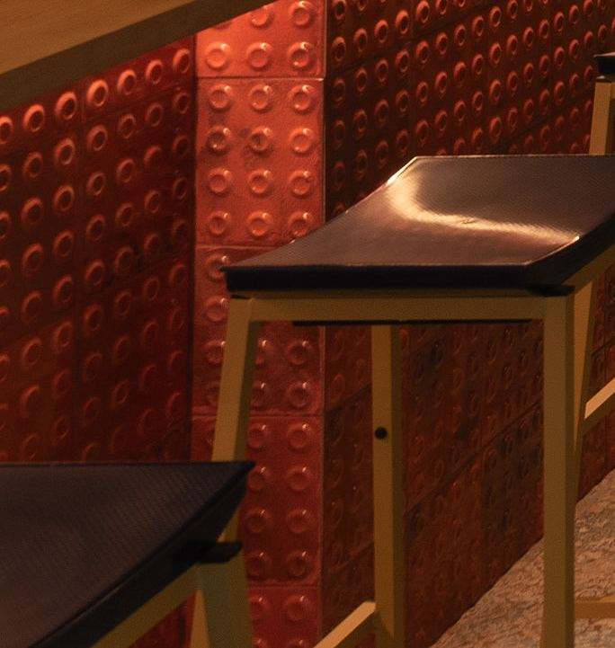 Detalle del frente de la barra: azulejo rojo con botones circulares en relieve bajo la encimera de madera.
