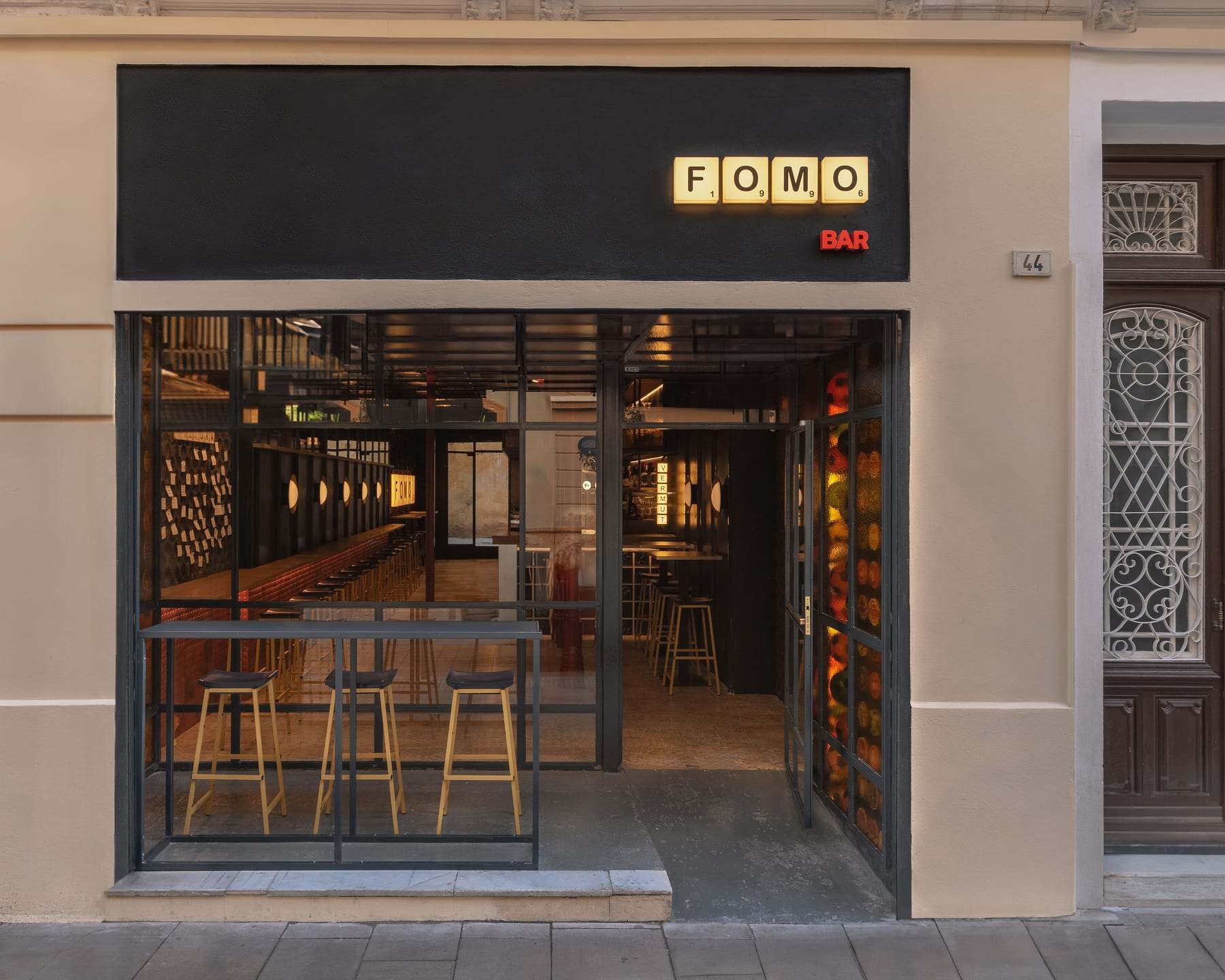 Fachada de FOMO Bar en calle Carretería 44, de día, con el rótulo de fichas FOMO BAR sobre la cristalera.