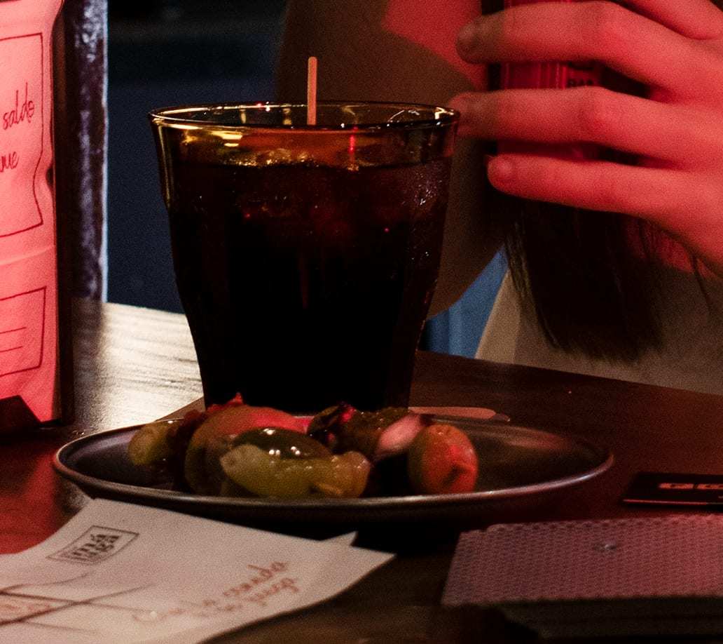 Vermut en vaso Duralex junto a un plato de gildas y aceitunas sobre la mesa.